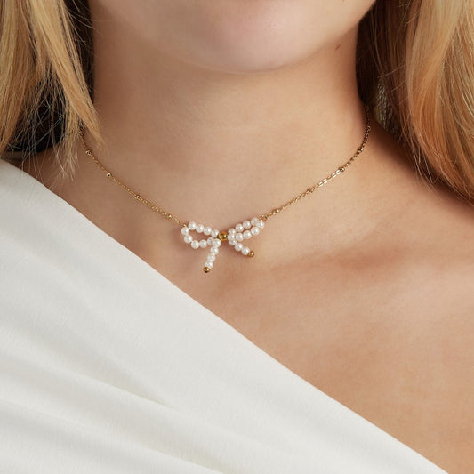 Elegante gouden ketting met een strikje en parel hangertje