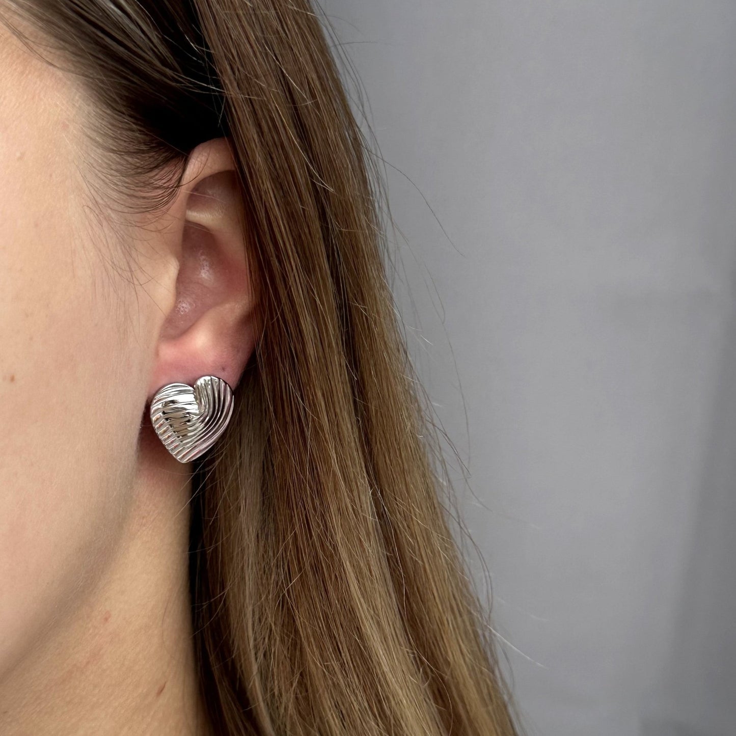 Trendy zilveren oorbel met een minimalistische hartvorm en strakke lijnen