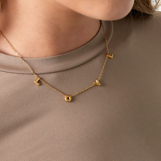 Delicate gouden ketting met letters die samen het woord "LOVE" vormen